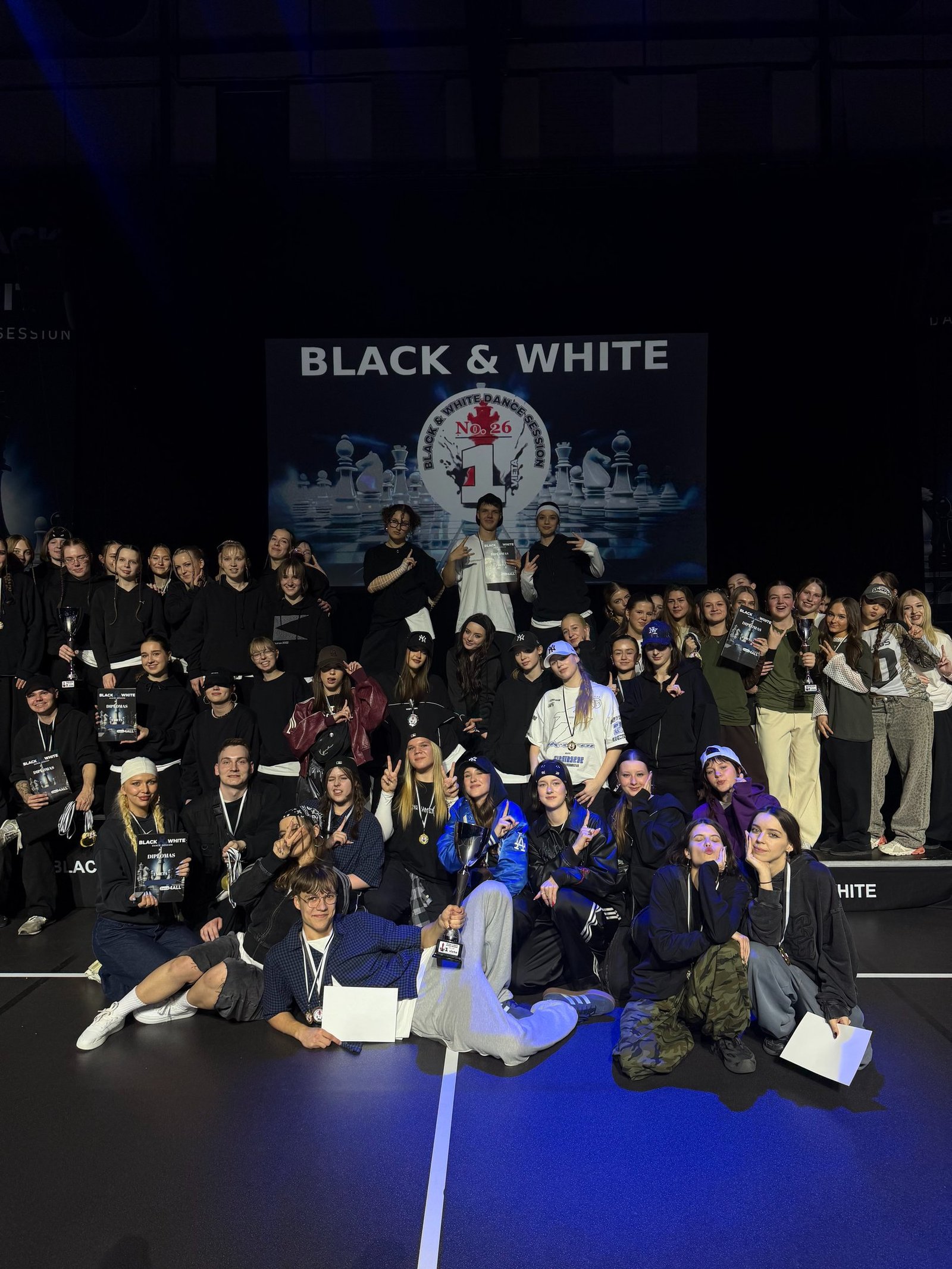 A group of hip hop dancers posing with trophies at the Black and White Dance Session competition.